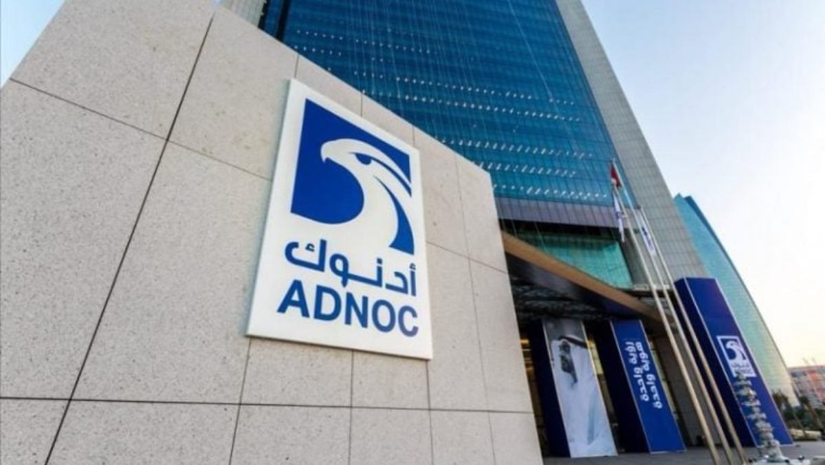ADNOC headquarters exterior with company logo sign and glass tower.