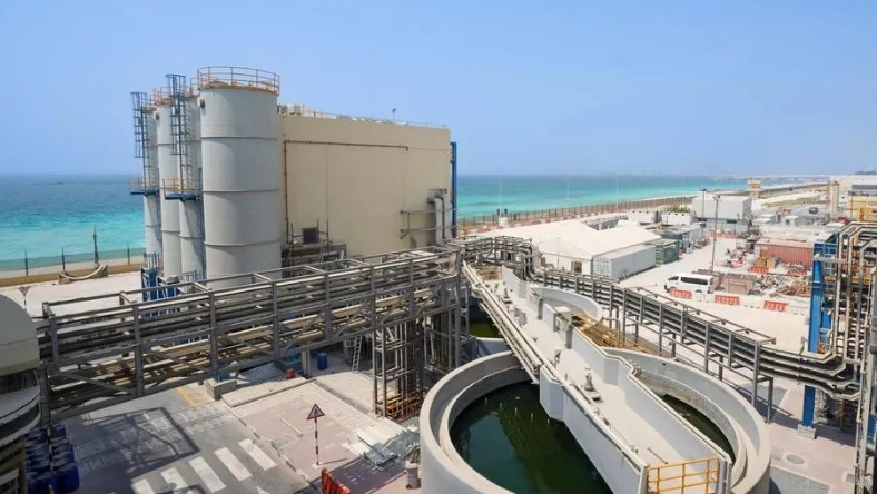 Coastal wastewater treatment facility with circular basin and industrial pipelines