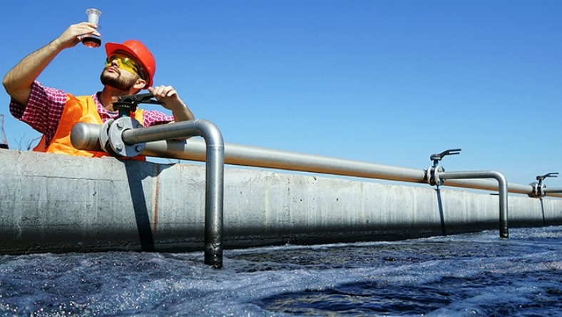 Industrial worker analyzing water sample at treatment facility